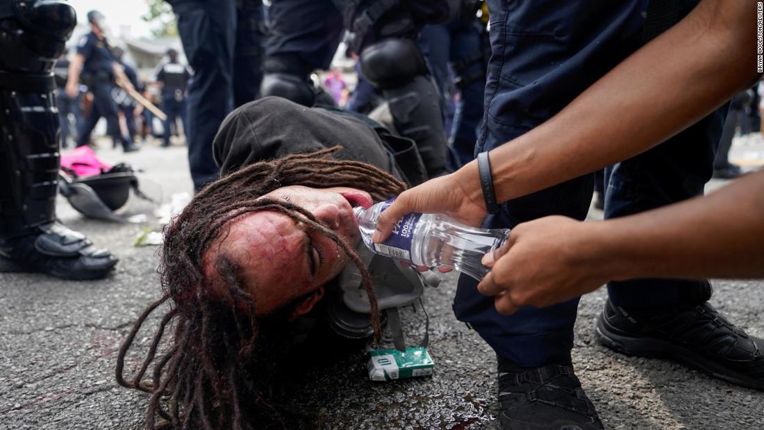 A protester in Louisville offers a detained man water.