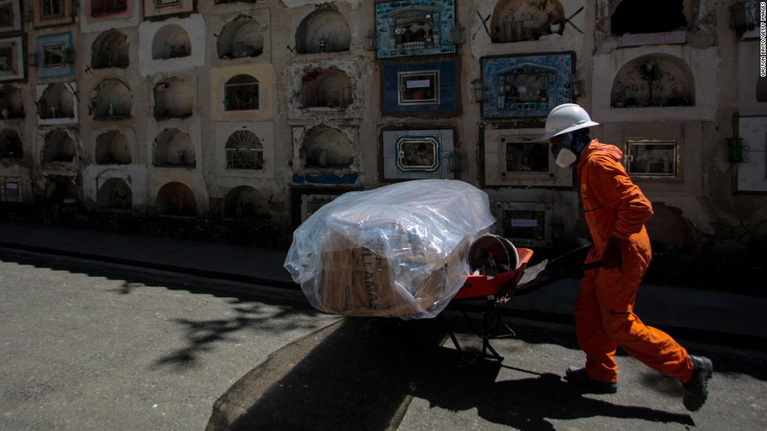 A cemetery worker in La Paz, Bolivia, pushes a cart with a plastic-wrapped coffin on September 23.