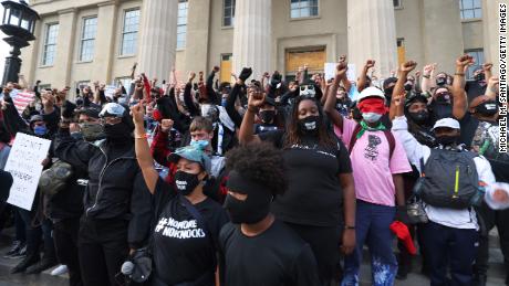 Demonstrators raise their fists as they gather on the steps of the Louisville Metro Hall on September 24, 2020.