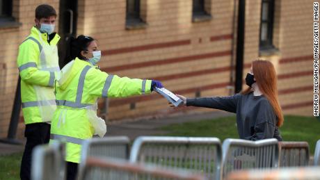 Staff from the UK&#39;s National Health Service (NHS) hand out test kits to Glasgow University students as they arrive at a pop up test center at the Murano Street Student Village residence.