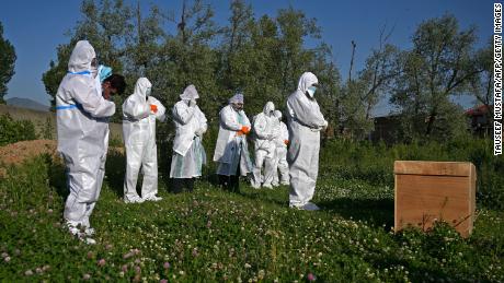 Relatives wearing personal protective equipment offer funeral prayers for a woman who died from the coronavirus, during her burial at a graveyard in Srinagar on May 21, 2020. 