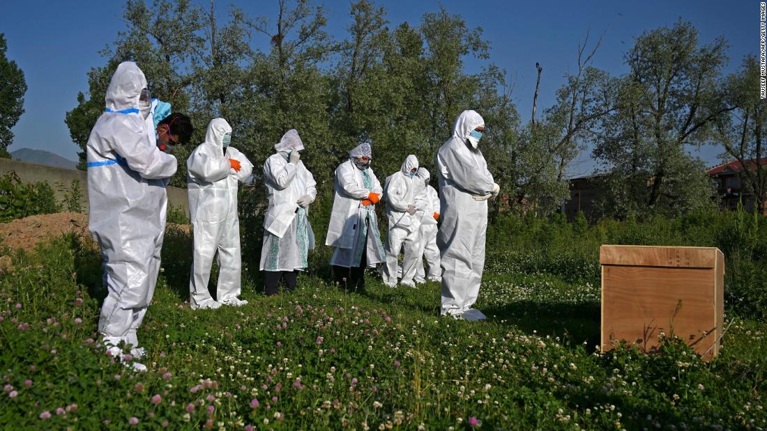 Relatives wearing personal protective equipment offer funeral prayers for a woman who died from the coronavirus, during her burial at a graveyard in Srinagar on May 21, 2020. 