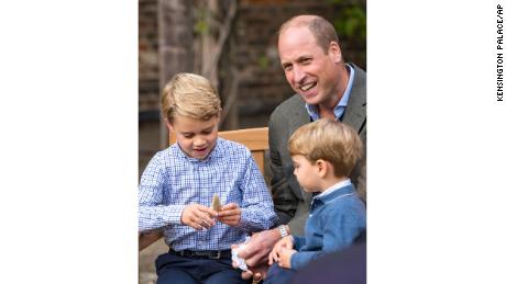 Prince William and Prince Louis examine the tooth of a giant shark given to them by Naturalist Sir David Attenborough in the gardens of Kensington Palace in London.