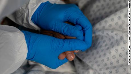 HOUSTON, TX - JULY 28:  (EDITORIAL USE ONLY) A member of the medical staff holds a patient&#39;s hand in the COVID-19 intensive care unit at the United Memorial Medical Center on July 28, 2020 in Houston, Texas. COVID-19 cases and hospitalizations have spiked since Texas reopened, pushing intensive-care units to full capacity and sparking concerns about a surge in fatalities as the virus spreads.  (Photo by Go Nakamura/Getty Images)