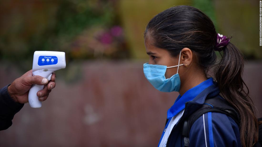 A student has her temperature checked before entering classes at a school in Thankot, Nepal, on September 30.