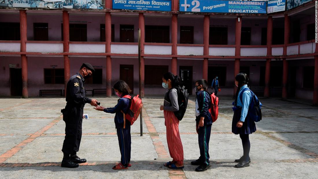 A security guard gives hand sanitizer to students as they arrive at the Prabhat secondary school on the outskirts of Kathmandu, Nepal, on October 6.