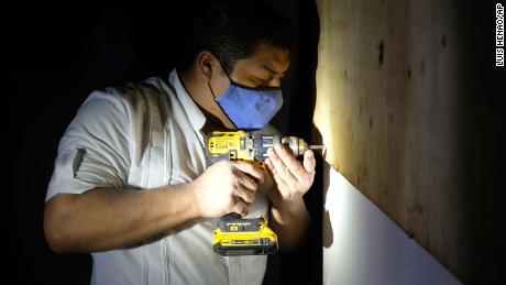 A hotel worker from the Fiesta Americana Condesa resort covers a window with plywood at a shelter set up at the Technological Institute of Cancun, as he prepares for the landfall of Hurricane Delta.