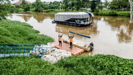 Local workers haul away trash collected by the autonomous Interceptor 001 anchored in the Cengkareng Drain waterway in Jakarta, Indonesia.