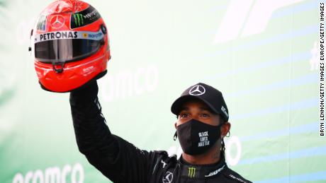 Lewis Hamilton holds aloft a helmet worn by Michael Schumacher after he tied the German legend&#39;s F1 win record at the Eifel GP.