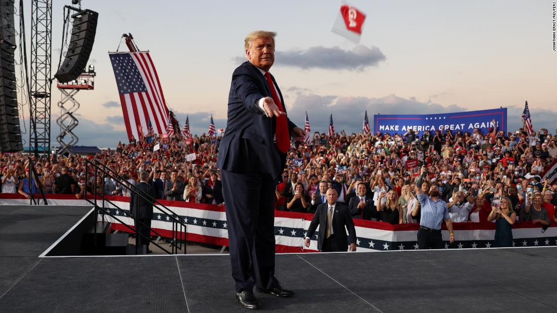 Trump tosses face masks to the crowd as he takes the stage for a campaign rally in Sanford, Florida, on October 12, 2020.
