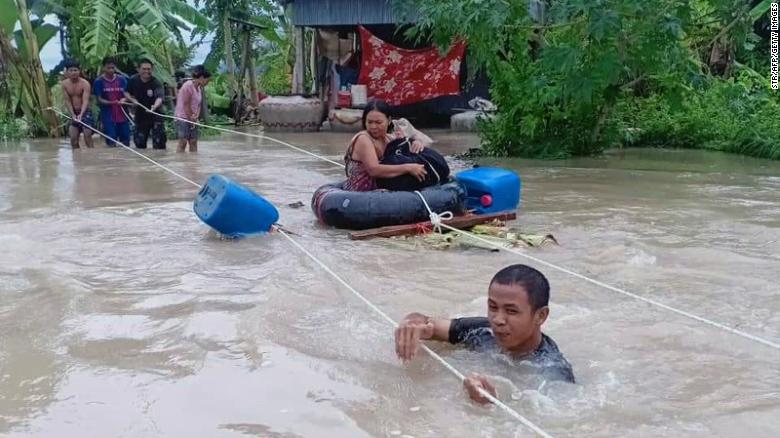 A soldier (front) holds onto a rope as a woman (C) is is pulled to safety through flood waters in a village in Cambodia's western Battambang province on October 10, 2020, following heavy rains in the region. (Photo by STR / AFP) (Photo by STR/AFP via Getty Images)