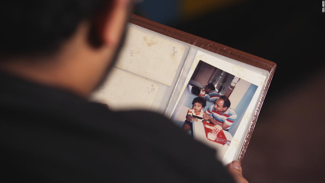 Jitarth Jadeja looks at a photo of himself as a child next to his father. (Bill Code for CNN Business)