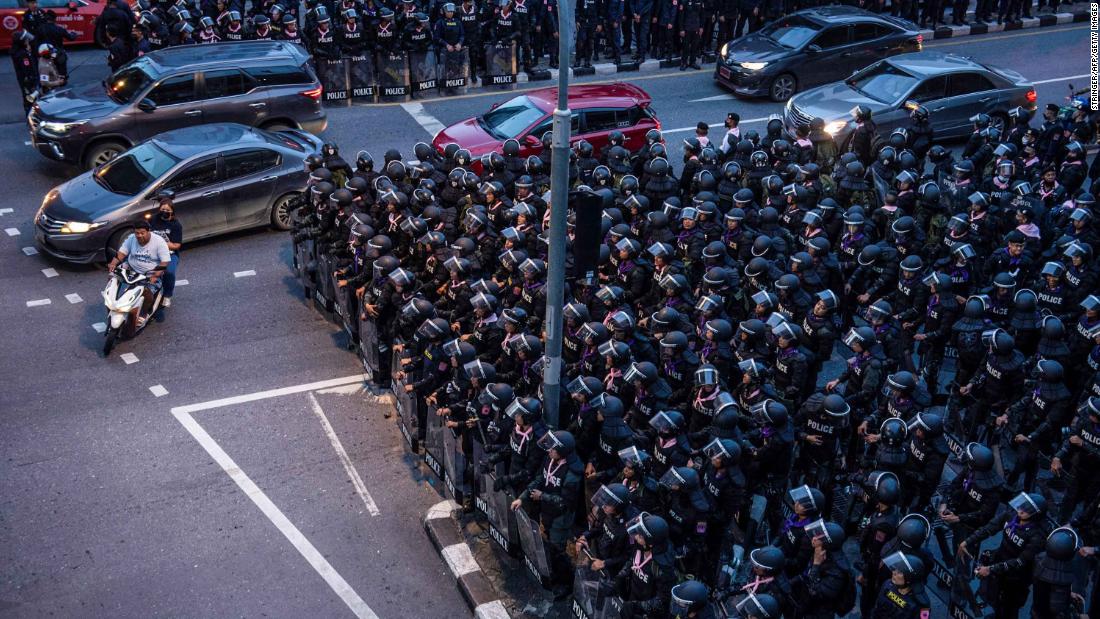 Motorists ride past riot police in Bangkok on October 15.