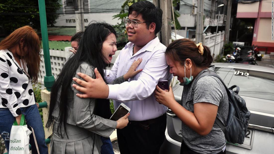 Pro-democracy activist Bunkueanun &quot;Francis&quot; Paothong, center, comforts loved ones before he enters the Dusit Police Station on October 16, to answer charges of harming Thailand&#39;s Queen Suthida, two days after protesters nearly obstructed a royal motorcade.