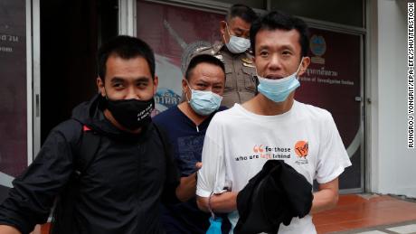 Le militant thaïlandais pour la démocratie Ekachai Hongkangwan (à droite) est escorté par des policiers après avoir été arrêté, au poste de police de Lat Phrao à Bangkok, le 16 octobre 2020. 