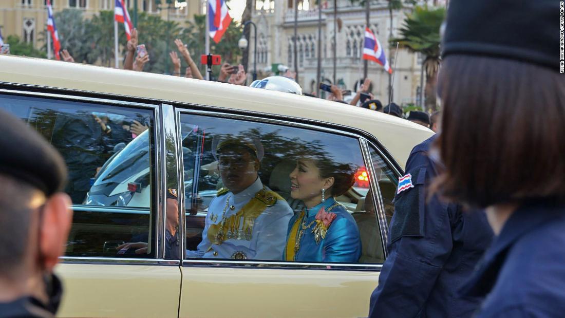 Thailand&#39;s Queen Suthida, center, and Prince Dipangkorn Rasmijoti, center-left, ride inside a royal motorcade as it drives past a pro-democracy rally on October 14.