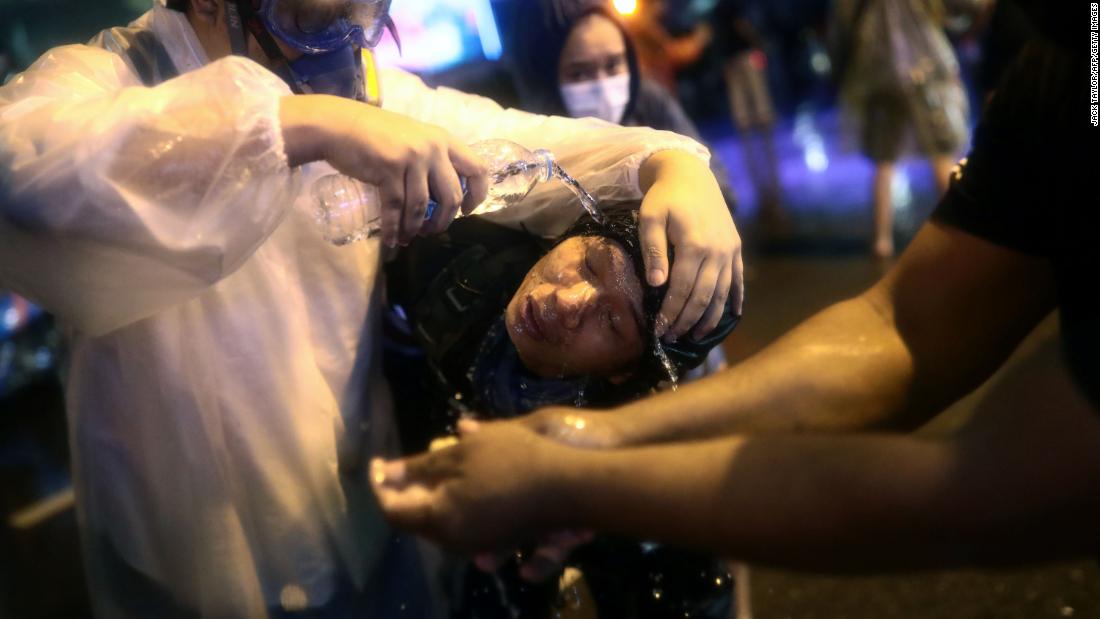 Protesters gather around a fellow pro-democracy activist to wash his face after police fired water cannons laced with pepper on October 16.
