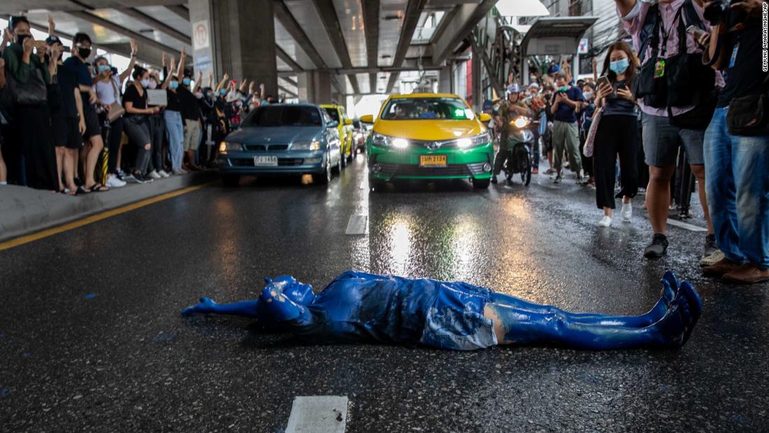 A protester covered in blue paint lies on a road during a protest in Udom Suk, in Bangkok&#39;s suburbs, on October 17. 