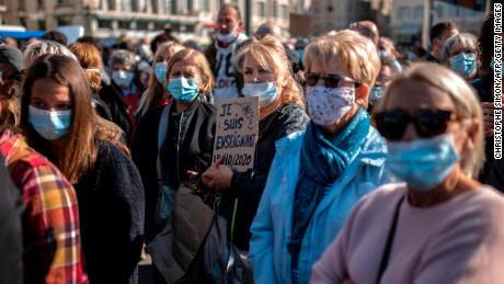 A woman holds a placard reading &quot;I am a teacher&quot; as people gather on the Vieux Port in Marseille on October 18, in homage to history teacher Samuel Paty.