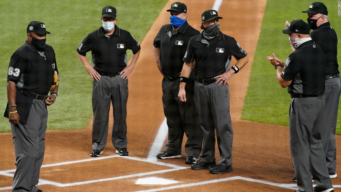 The umpire crew, all wearing masks due to coronavirus protocols, stands at home plate before Game 1.