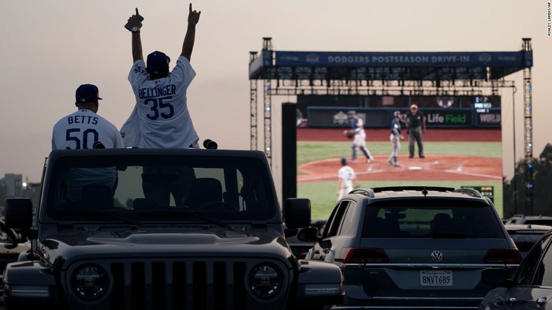 Mike Kim and Jacob Zelaya cheer from their car while watching the game outside Dodger Stadium in Los Angeles. Due to the coronavirus pandemic, Major League Baseball decided to play all World Series games at a neutral site in Arlington, Texas.