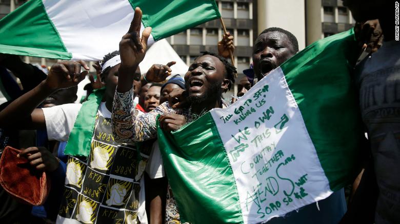 People hold up banners as they protest against police brutality in Lagos, Nigeria, on Tuesday.