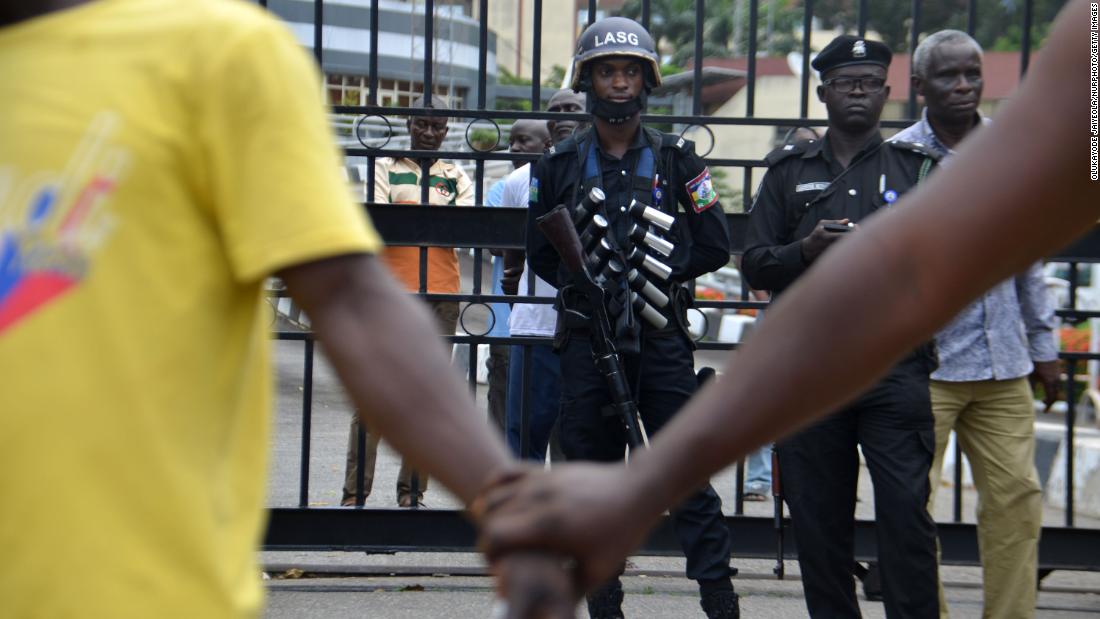 Protesters hold hands in front of police officers during a peaceful demonstration at the Alausa Secretariat.