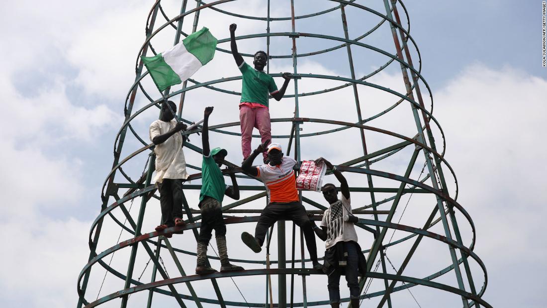 Protesters climb a telecommunications tower during a demonstration in Abuja on Monday, October 19.