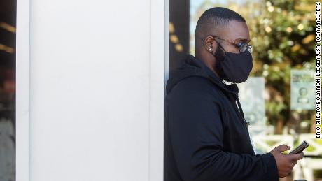 Nike Factory Store employee David Sturgis checks his text messages while wearing a mask at the Outlets of Mississippi in Pearl.