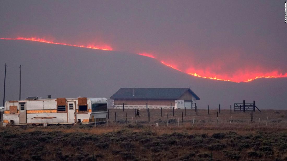 Flames rise from mountain ridges near a farmstead as a wildfire burns near Granby, Colorado, on Thursday, October 22.