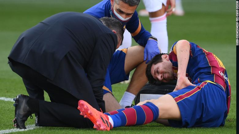 Messi receives medical attention after being tackled during the game against Real Madrid.