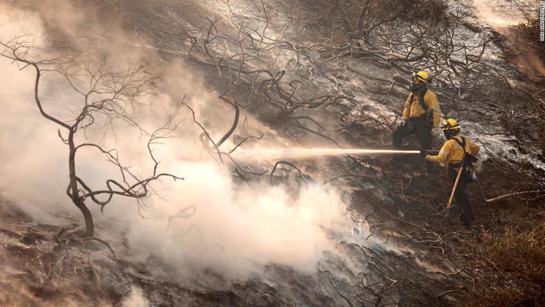 A firefighter uses a hose as the Silverado Fire approaches near Irvine, California.