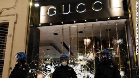 Italian police officers stand in front of a shattered Gucci store window during a protest of far-right activists against the government restriction measures to curb the spread of COVID-19, in downtown Turin, on October 26, 2020, as the country faces a second wave of infections to the Covid-19 (the novel coronavirus). - Italy&#39;s Prime Minister Giuseppe Conte tightened nationwide coronavirus restrictions on October 25, 2020 after the country registered a record number of new cases, despite opposition from regional heads and street protests over curfews. Cinemas, theatres, gyms and swimming pools must all close under the new rules, which come into force on October 26, 2020 and run until November 24, while restaurants and bars will stop serving at 6pm, the prime minister&#39;s office said. (Photo by Marco BERTORELLO / AFP) (Photo by MARCO BERTORELLO/AFP via Getty Images)