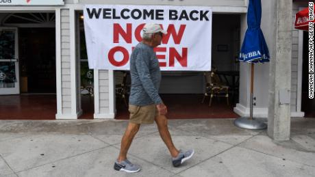 A man walks past a sign reading &quot;Welcome Back, Now Open&quot; on Fort Lauderdale Beach Boulevard in Fort Lauderdale, Florida on May 18, 2020. - South Florida begins a gradual reopening of its economy on May 18,2020 with the start of activities of some restaurants and businesses in Miami and Fort Lauderdale, but the beaches will still be closed until further notice.The opening &quot;phase 1&quot; in this region also does not include hotels, bars, nightclubs, gyms, movie theatres or massage parlours. (Photo by Chandan Khanna/AFP/Getty Images)