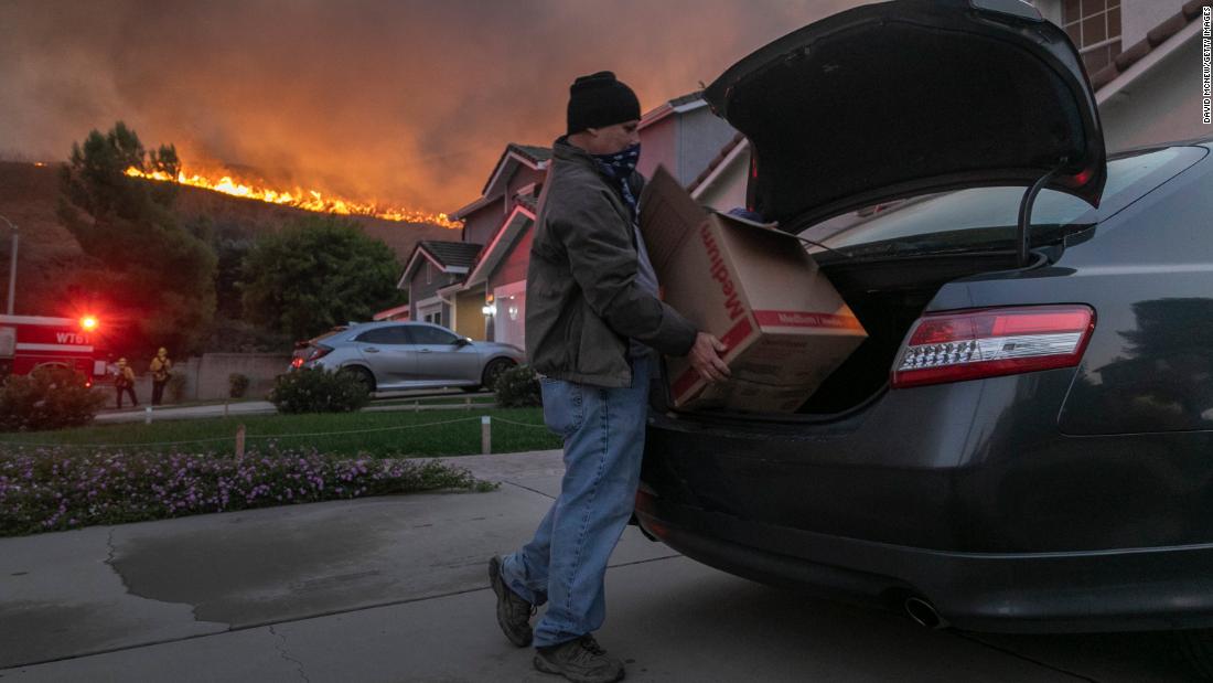 A man evacuates his home as flames from the Blue Ridge Fire approach in Chino Hills, California, on Tuesday, October 27, 2020.