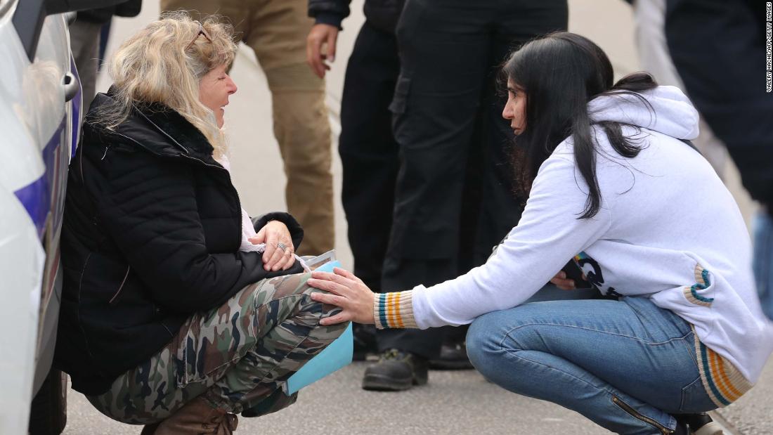 A woman is comforted as she kneels by a police car following the attack.