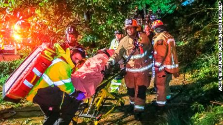 Atlanta firefighters transport a man they freed who was trapped in his third-floor bedroom after a tree came down on a home Thursday. 