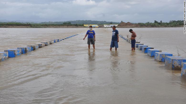 Residents wade in a flooded bridge over a swollen river due to heavy rains in Ilagan town, north of Manila, on October 31 ahead of Typhoon Goni's landfall in the Philippines.