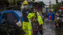 MANILA, PHILIPPINES - NOVEMBER 01: A rescue worker covers children in a raincoat as they evacuate before Typhoon Goni hits on November 1, 2020 in Manila, Philippines. Super Typhoon Goni, this year&#39;s most powerful storm in the world, has made landfall in the Philippines with wind gusts of up to 165 miles per hour early Sunday. At least two people have been killed so far and hundreds of thousands have been evacuated ahead of the storm. (Photo by Ezra Acayan/Getty Images)