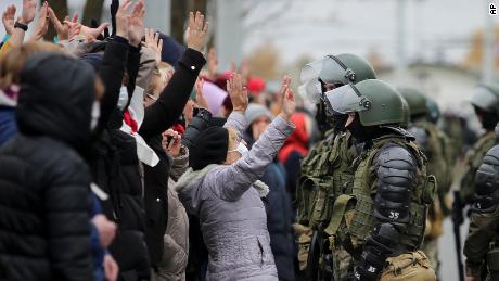 Demonstrators stand with their hands up in front of riot police in Minsk on Sunday.