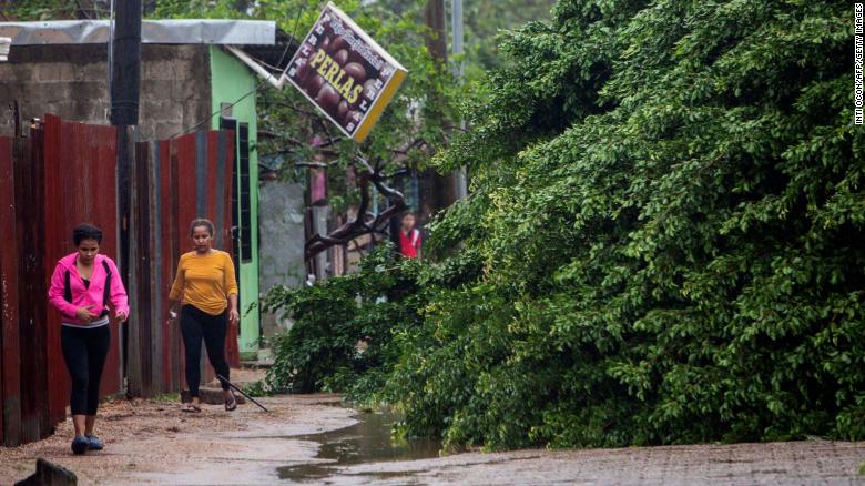 Women walk next to fallen trees Tuesday morning in Puerto Cabezas, Nicaragua, after winds from Hurricane Eta raked the area.