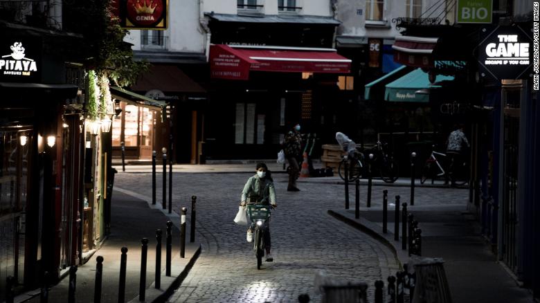 A woman rides a bike along an empty street in the district of St. Michel in Paris on November 3, the fifth day of France's lockdown.