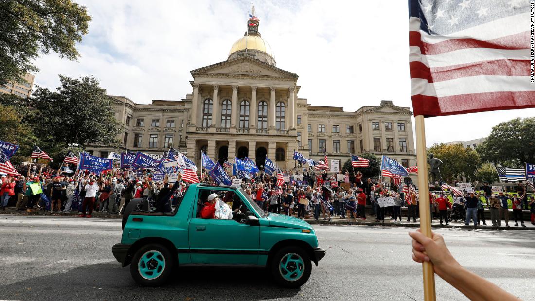 A Biden supporter drives past Trump supporters who had gathered in front of the Georgia State Capitol in Atlanta.