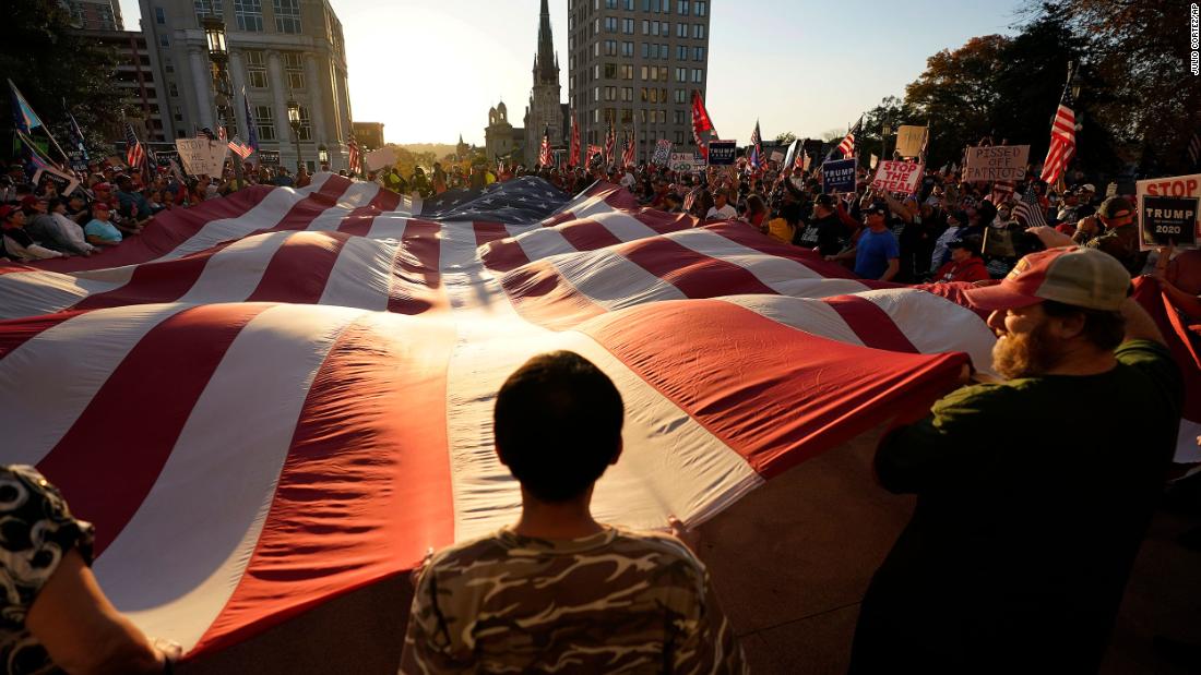 Supporters of President Donald Trump unfurl a giant American flag outside the State Capitol in Harrisburg, Pennsylvania, after Biden&#39;s win was projected on November 7.