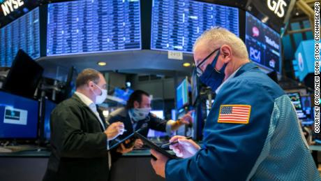 In this photo provided by the New York Stock Exchange, James Dresch, right, works with fellow traders on the floor, Monday Nov. 9, 2020. Stocks around the world are surging Monday, sending Wall Street back to record heights, on a burst of hope following encouraging data for a potential COVID-19 vaccine from Pfizer. (Courtney Crow/New York Stock Exchange/AP)