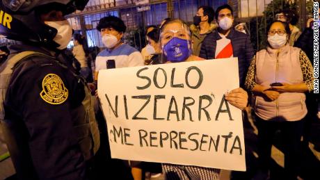 A woman displays a banner reading &#39;Only Vizcarra represents me&#39; in Spanish as former President Vizcarra arrives home in Lima on November 9.