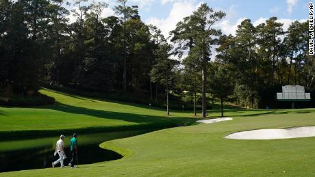 DeChambeau and Tiger Woods walk up the 15th fairway during a practice round at the Masters.