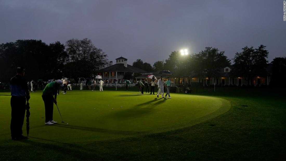 Golfers practice on the putting green next near the Augusta National Golf Course clubhouse before the start of the first round in near darkness. 