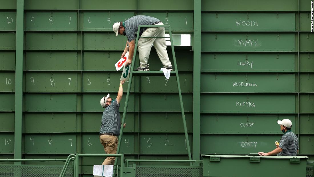 Course workers fill the scoreboard on the 15th hole during the first round.