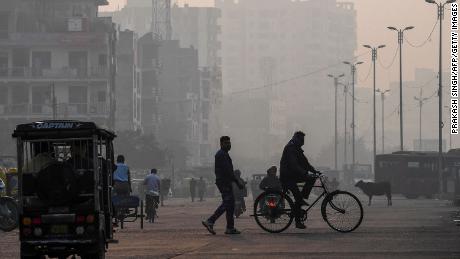 People make their way along the street amidst the conditions of smog in New Delhi on November 15, 2020. 